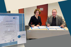 Schulleiter Klaudius Zdriliuk und Bettina Bertalan, Leiterin der Serviceeinheit "Vergleichende Biologie", unterschreiben die Vereinbarung